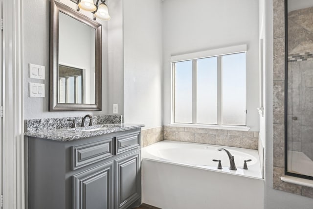 bathroom with tiled shower, vanity, and a bath