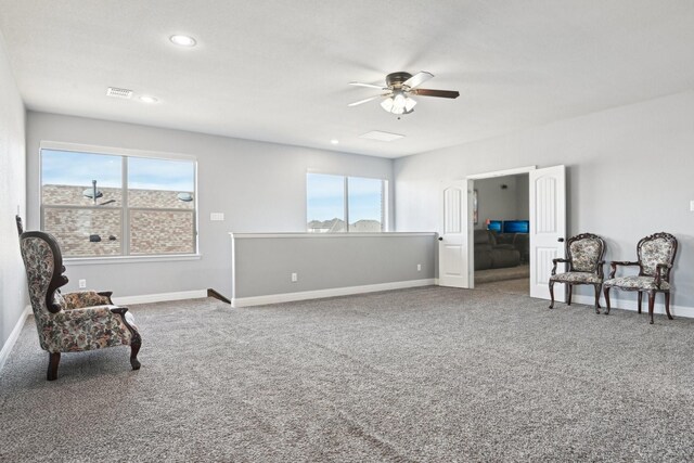 living area featuring carpet floors, visible vents, ceiling fan, and baseboards