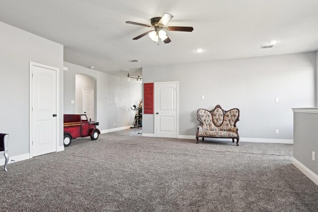 unfurnished room featuring arched walkways, carpet floors, visible vents, a ceiling fan, and baseboards
