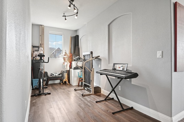 workout room with track lighting, baseboards, and wood finished floors