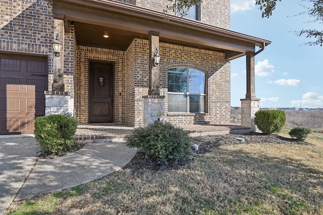entrance to property with covered porch, brick siding, and an attached garage