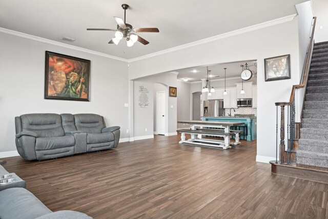 living room with crown molding, dark wood finished floors, visible vents, baseboards, and stairs
