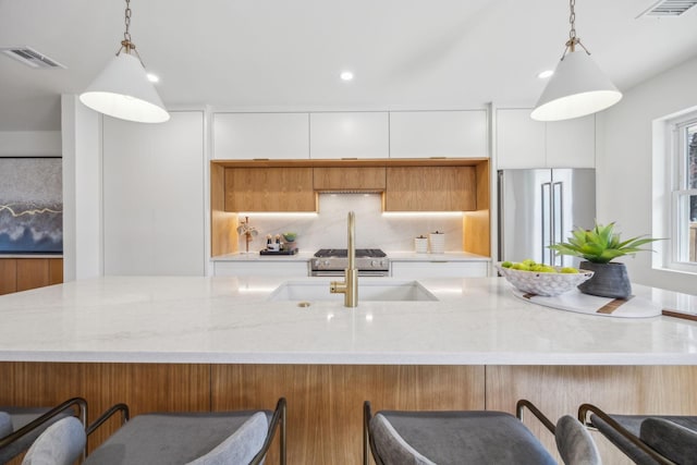 kitchen featuring white cabinetry, decorative light fixtures, high end appliances, and tasteful backsplash