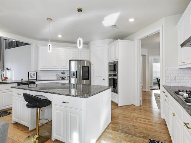 kitchen with white cabinets, a center island, pendant lighting, and appliances with stainless steel finishes