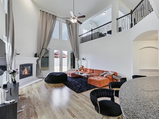 living room featuring a high ceiling, ceiling fan, french doors, and wood-type flooring