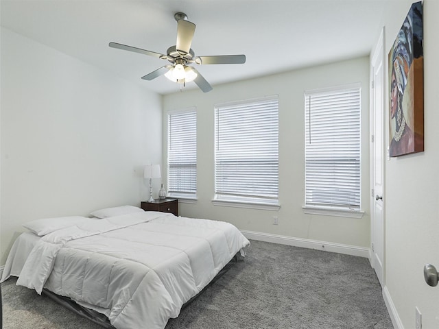 bedroom with ceiling fan, multiple windows, and dark colored carpet