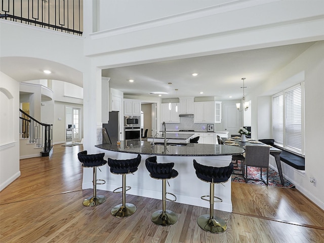 kitchen with kitchen peninsula, stainless steel appliances, backsplash, white cabinetry, and sink