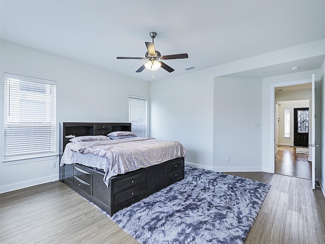 bedroom featuring multiple windows, ceiling fan, and dark wood-type flooring