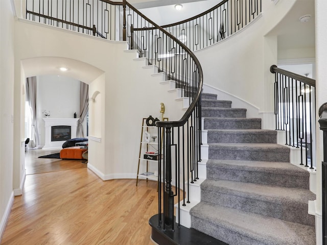 staircase featuring a towering ceiling and hardwood / wood-style flooring