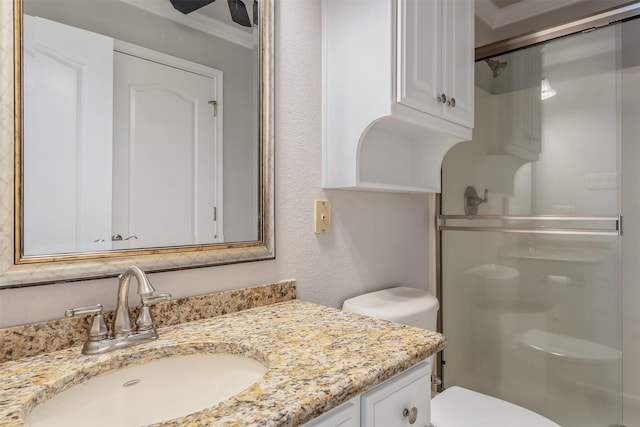 bathroom with crown molding, a shower with door, vanity, and toilet