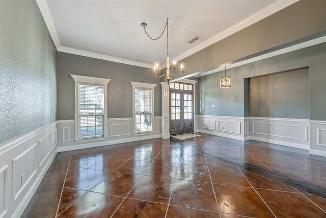 unfurnished dining area with french doors, ornamental molding, dark tile patterned flooring, and an inviting chandelier