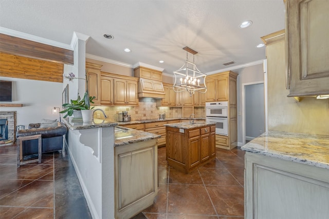 kitchen with black electric stovetop, light stone countertops, decorative light fixtures, a kitchen island, and kitchen peninsula