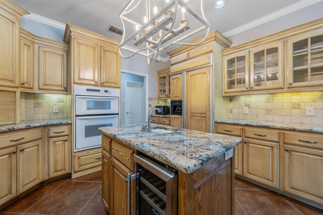 kitchen featuring tasteful backsplash, double oven, beverage cooler, decorative light fixtures, and an island with sink