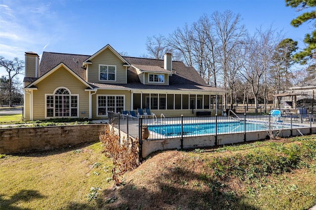 back of property with a fenced in pool and a sunroom