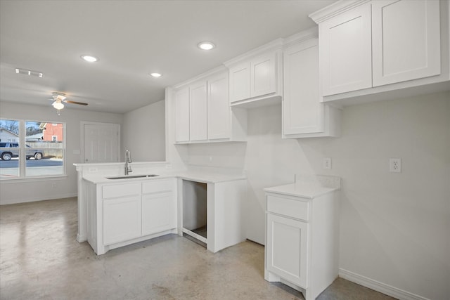 kitchen featuring ceiling fan, kitchen peninsula, sink, and white cabinets