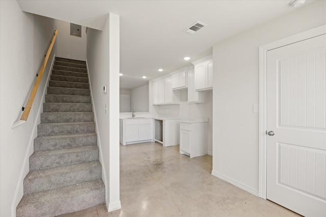 stairs with sink and concrete floors