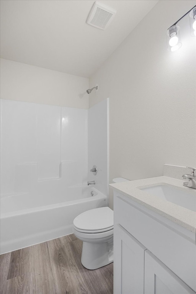 full bathroom with vanity, hardwood / wood-style floors, bathing tub / shower combination, and toilet