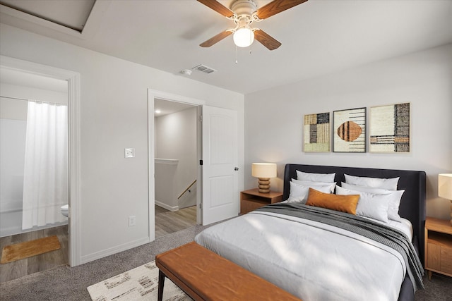 carpeted bedroom with ensuite bathroom and ceiling fan