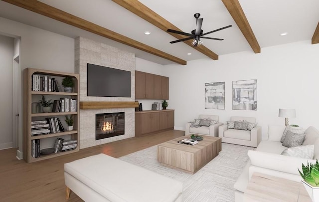 living room featuring a fireplace, light hardwood / wood-style floors, beamed ceiling, and ceiling fan