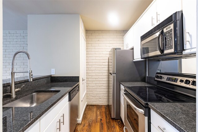 kitchen featuring white cabinetry, brick wall, and appliances with stainless steel finishes