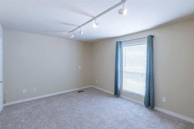 carpeted spare room featuring rail lighting