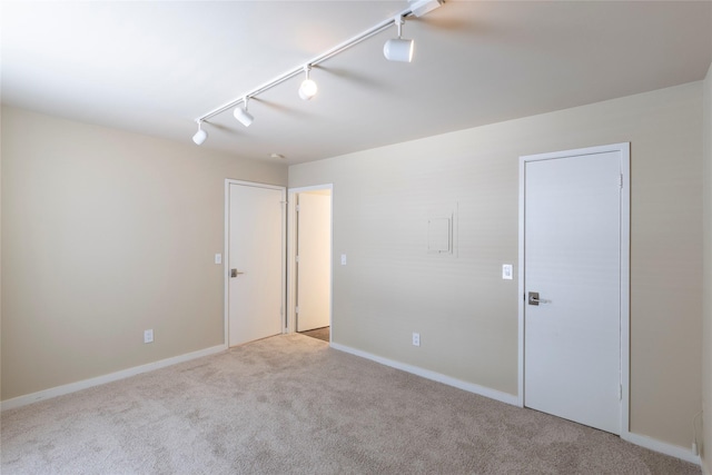 spare room featuring light colored carpet and track lighting