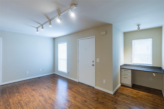 entrance foyer featuring dark hardwood / wood-style flooring, rail lighting, and built in desk