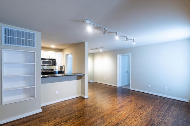 kitchen featuring kitchen peninsula, dark hardwood / wood-style floors, built in features, white cabinetry, and stainless steel appliances