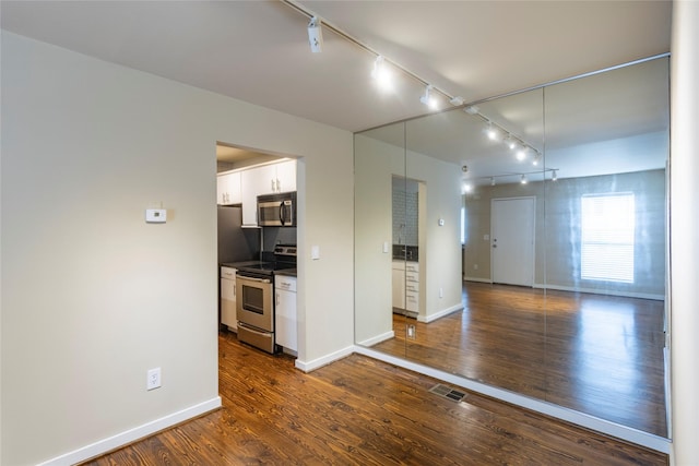 kitchen featuring white cabinets, appliances with stainless steel finishes, rail lighting, and dark hardwood / wood-style floors