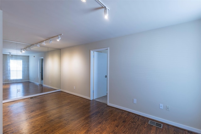 empty room featuring rail lighting and dark hardwood / wood-style floors