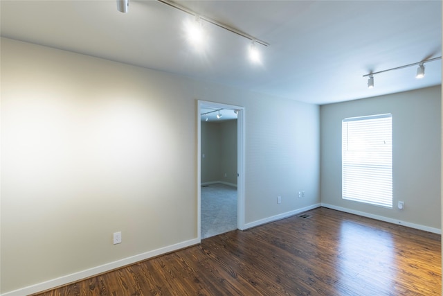 spare room featuring dark hardwood / wood-style floors and track lighting