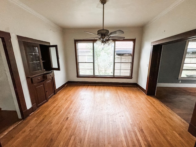 unfurnished dining area with ceiling fan, light wood-type flooring, and ornamental molding