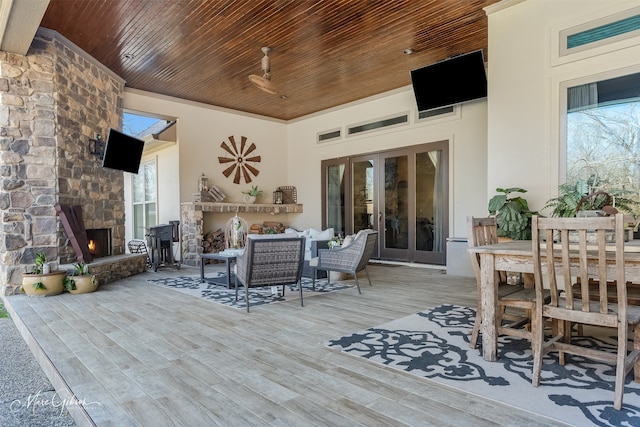 wooden deck featuring french doors, ceiling fan, and an outdoor living space with a fireplace