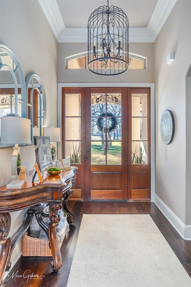 entryway with ornamental molding, dark wood-type flooring, and a chandelier