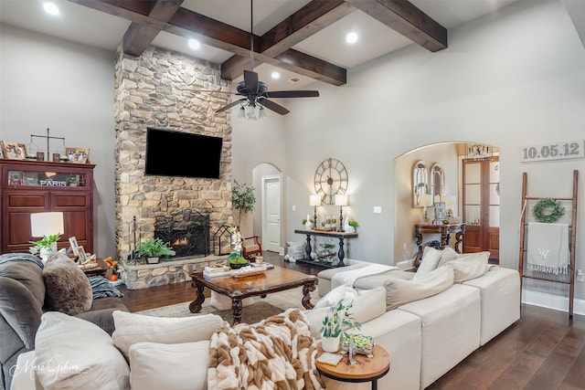 living room featuring beamed ceiling, ceiling fan, dark wood-type flooring, and a fireplace