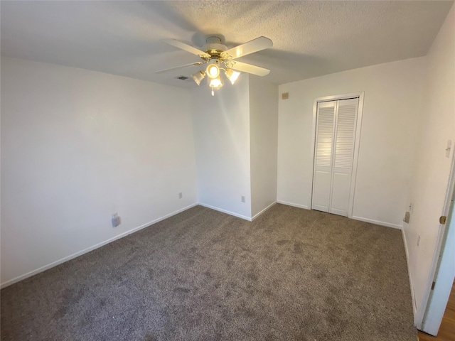 unfurnished bedroom featuring dark colored carpet, a closet, and ceiling fan