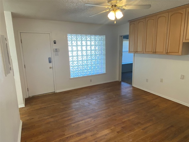 interior space with a textured ceiling, ceiling fan, and dark wood-type flooring