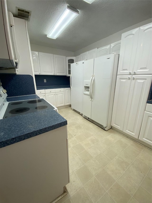 kitchen with range, a textured ceiling, white cabinetry, and white fridge with ice dispenser