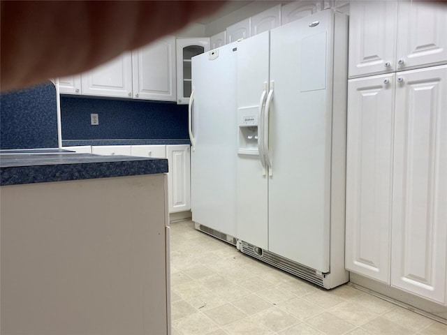 kitchen featuring white cabinetry and white fridge with ice dispenser