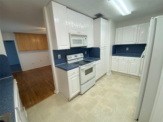 kitchen with backsplash, white cabinetry, a textured ceiling, and white appliances