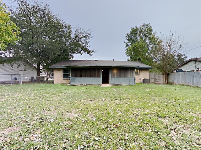 rear view of property featuring a yard and a sunroom