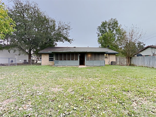 rear view of house featuring a yard and a sunroom