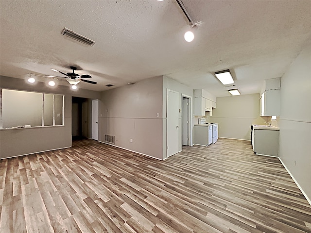 basement with a textured ceiling, light wood-type flooring, rail lighting, and ceiling fan