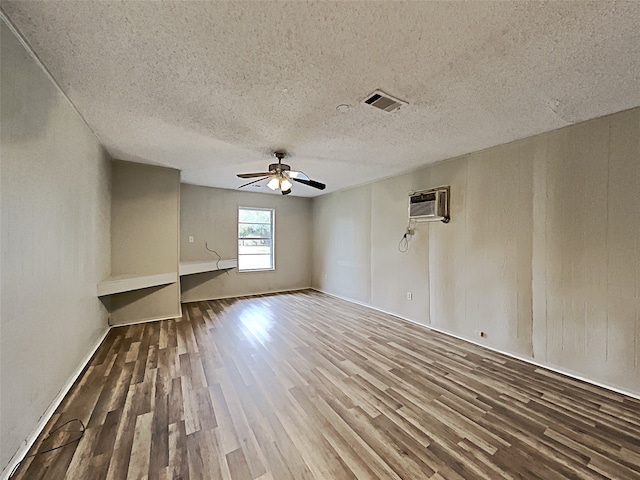 unfurnished living room featuring hardwood / wood-style floors, a textured ceiling, a wall mounted AC, and ceiling fan