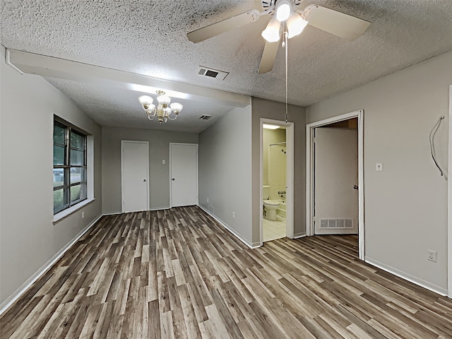 spare room with a textured ceiling, hardwood / wood-style floors, and ceiling fan with notable chandelier