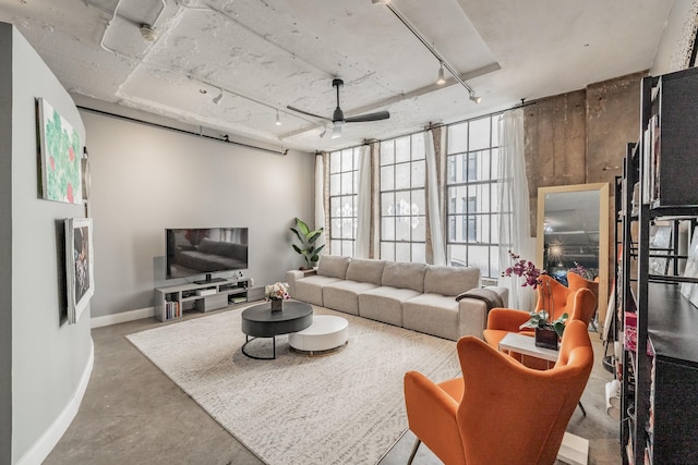 living room featuring ceiling fan, rail lighting, and concrete floors