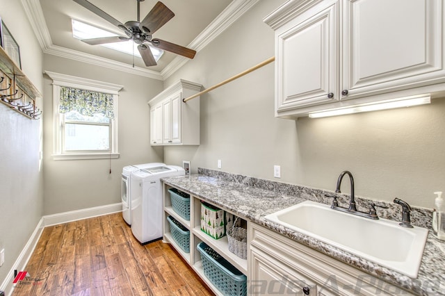 washroom featuring washing machine and clothes dryer, sink, dark wood-type flooring, cabinets, and crown molding