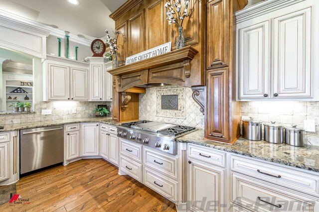 kitchen with backsplash, light stone counters, hardwood / wood-style floors, and appliances with stainless steel finishes