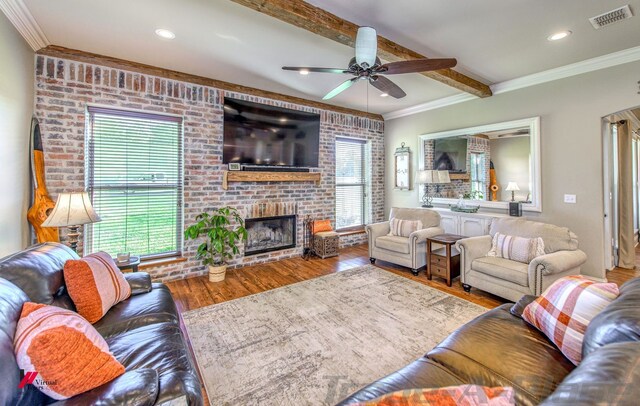 living room with beamed ceiling, hardwood / wood-style floors, a wealth of natural light, and a brick fireplace