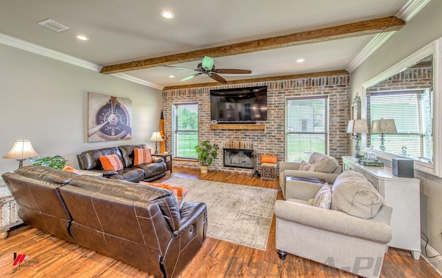 living room featuring hardwood / wood-style floors, ceiling fan, brick wall, and a brick fireplace